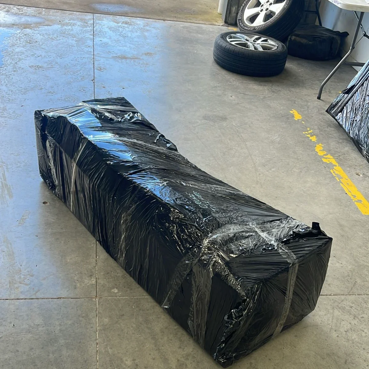 Large wrapped automotive part with car wheels and tires in auto repair shop ready for same day courier pickup
