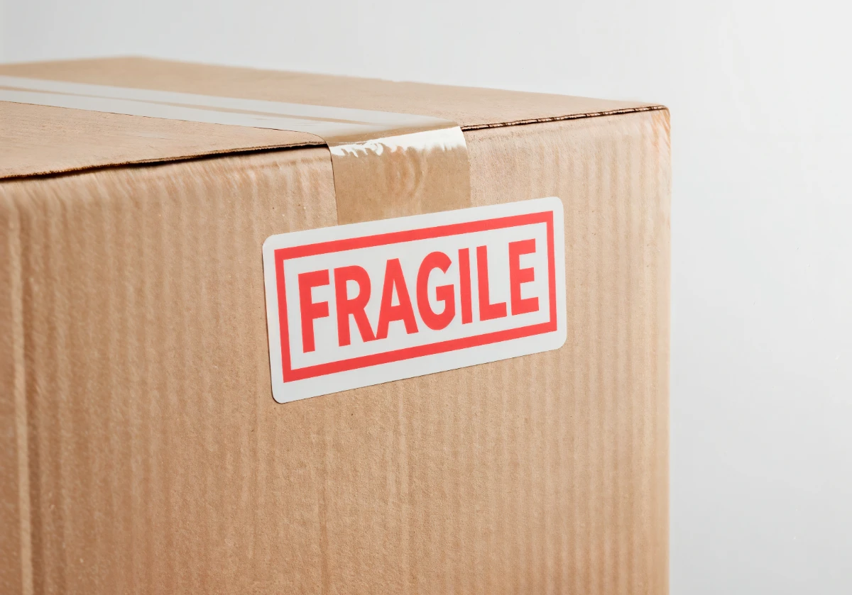 Cardboard shipping box with red fragile sticker label showing special handling requirements for courier delivery